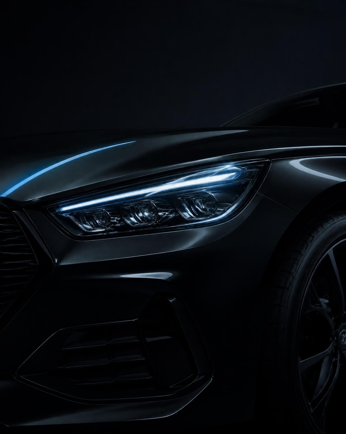 Headlight detail of a black luxury car in a dark studio